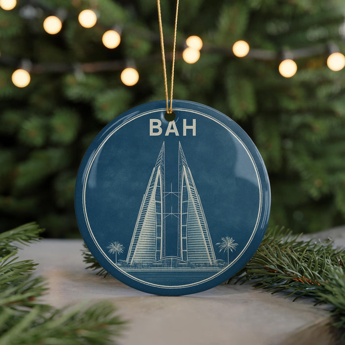 A blue circular ornament with a white illustration of a tall building and palm trees, hanging from a string.