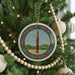 A Christmas tree decorated with ornaments, including a circular ornament featuring a musical instrument and a beaded garland.
