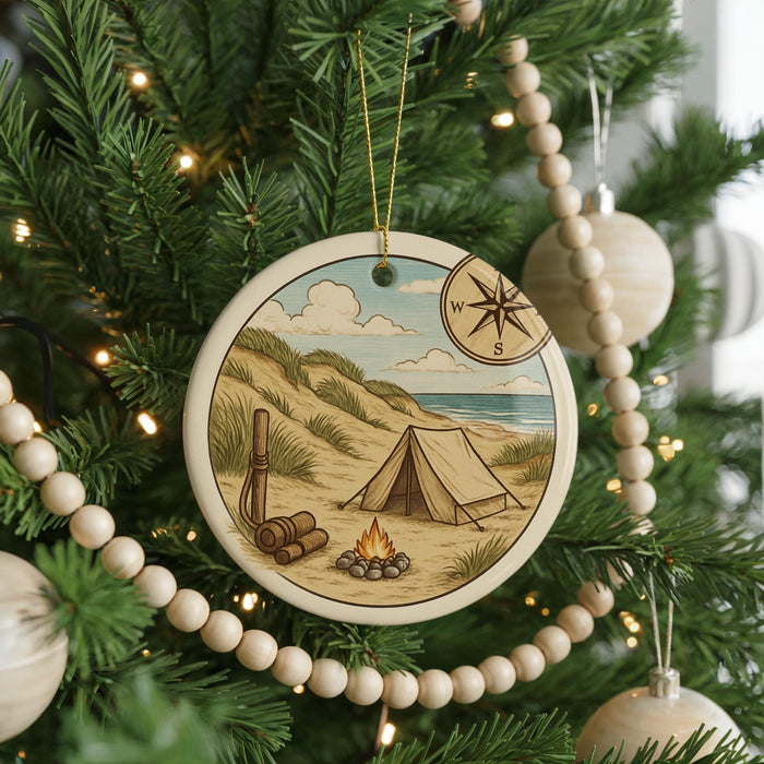 A Christmas tree decorated with a circular ornament featuring a camping scene with a tent, campfire, and compass.