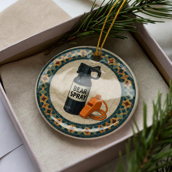 A decorative ornament in a box, featuring a black spray bottle and a whistle, with a tiled border.