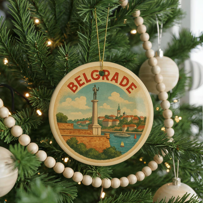 A round ornament on a Christmas tree, featuring a picture of a monument and the word "Belgrade" written on it.