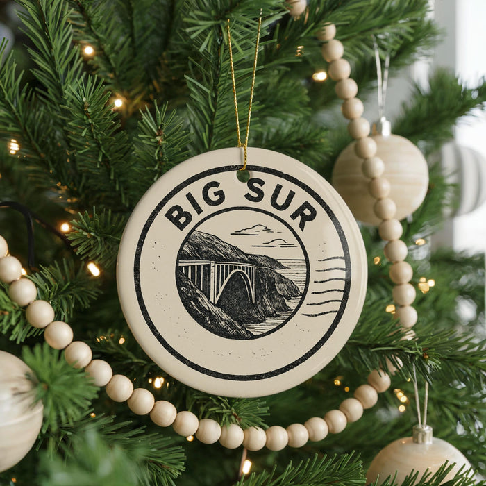 A Christmas tree decorated with ornaments, including a large circular ornament with the text "BIG SUR" and a bridge illustration.