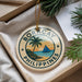 A round ornament with the text "BORACAY PHILIPPINES" and a graphic of a palm tree and sailboat, placed in a box with pine branches.