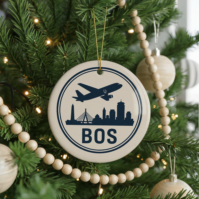 A Christmas tree decorated with ornaments, including a circular ornament with a silhouette of a city skyline and an airplane, and a beaded ornament.