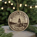 A circular ornament with the text "BOSPORUS Straat" and "TURKIYE" printed on it, along with a drawing of a bridge and a tower, is displayed in front of a Christmas tree with twinkling lights.