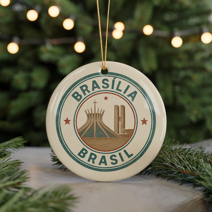A circular ornament with the text "Brasilia Brasil" and an illustration of the Christ Church Cathedral in Brasilia, Brazil, is displayed in front of a Christmas tree with twinkling lights.