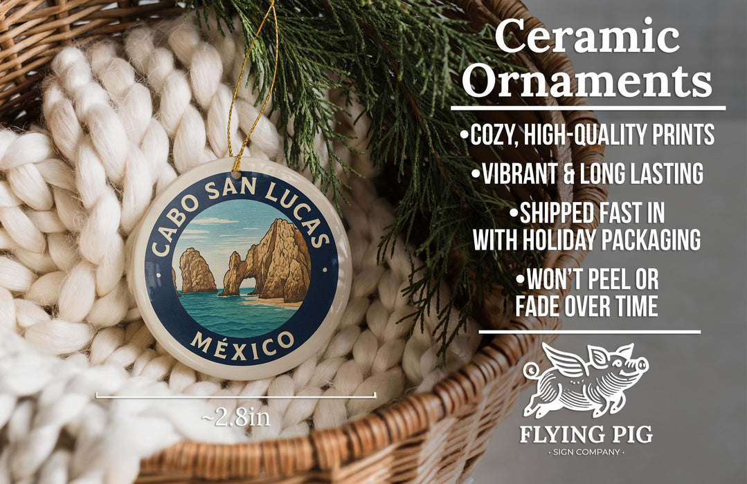 Ceramic ornaments, featuring a design of Cabo San Lucas, Mexico, hanging in a basket with pine branches.