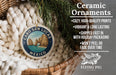 Ceramic ornaments, featuring a design of Cabo San Lucas, Mexico, hanging in a basket with pine branches.