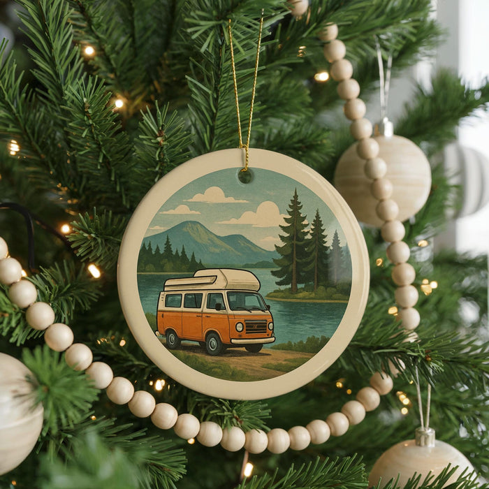 A Christmas tree decorated with ornaments, including a circular ornament featuring a van on a road surrounded by pine trees and mountains.