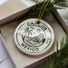 A ceramic ornament with the text "CANCUN MEXICO" printed on it, surrounded by a decorative border and a palm tree illustration.
