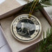 A decorative ornament in a box, featuring a dog and stars, with the text "CANIS MAJOR" around the edge.
