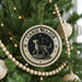 A Christmas tree decorated with ornaments, including a circular ornament with a dog and stars, and a string of wooden beads.