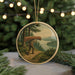 A circular ornament featuring a person carrying a large brown canoe, set against a scenic landscape with a lake and forest in the background.