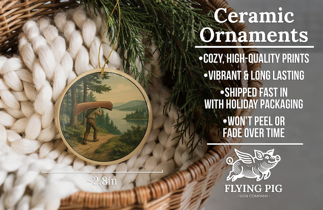 Ceramic ornaments, featuring a person carrying a canoe, are displayed in a basket with pine branches.