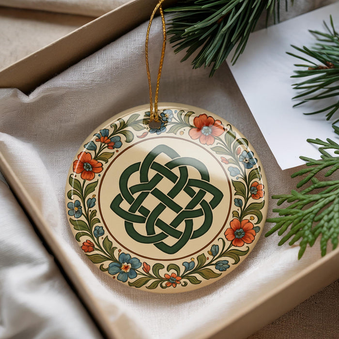 A decorative ornament with a Celtic knot design is displayed in a box, surrounded by pine branches and greenery.