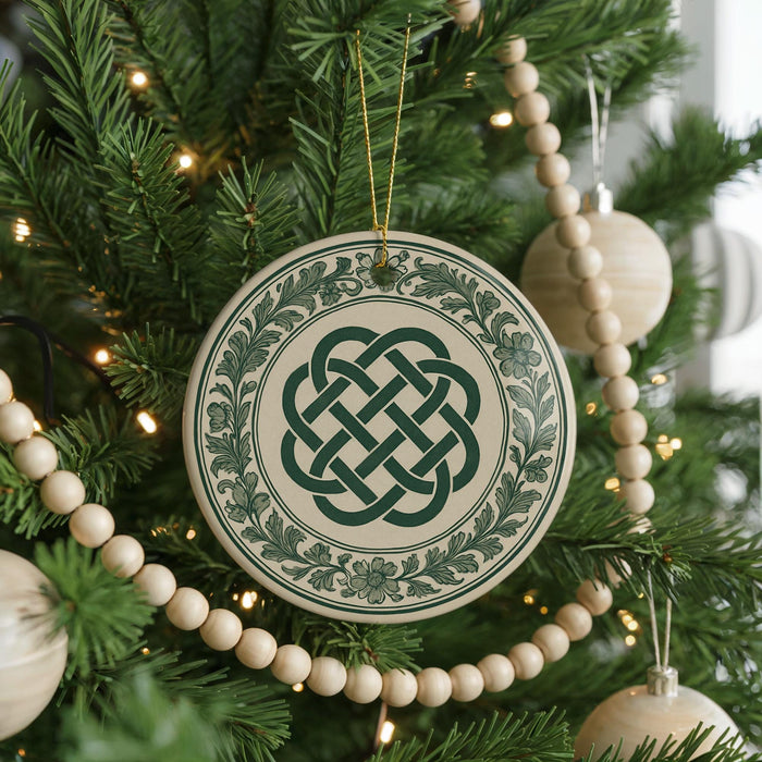 A Christmas tree decorated with ornaments, including a large circular ornament with a Celtic knot design, surrounded by green pine branches and white beads.