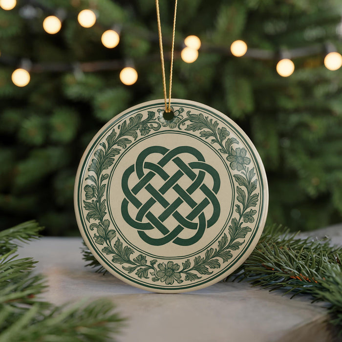 A decorative ornament with a Celtic knot design is displayed on a table, surrounded by pine branches and twinkling lights.