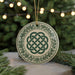 A decorative ornament with a Celtic knot design is displayed on a table, surrounded by pine branches and twinkling lights.