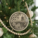 A Christmas tree decorated with ornaments, including a circular ornament with a floral design and a pagoda in the background.