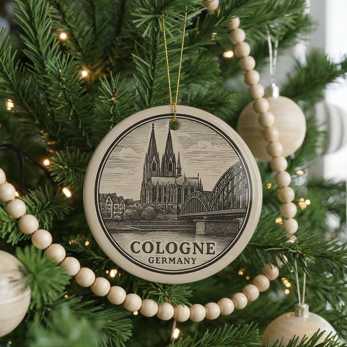 A circular ornament on a Christmas tree, featuring an illustration of the Cologne Cathedral in Germany.