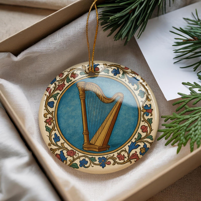 A decorative ornament featuring a harp is displayed in a box, surrounded by pine branches and a white card.
