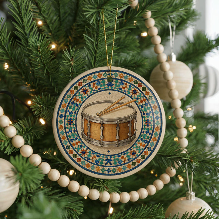 A Christmas tree decorated with ornaments, including a round ornament with a drum and a beaded garland.