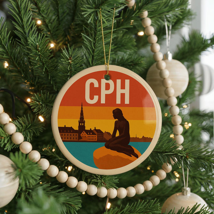 A Christmas tree decorated with ornaments, including a circular ornament with a silhouette of a person and a cityscape in the background.