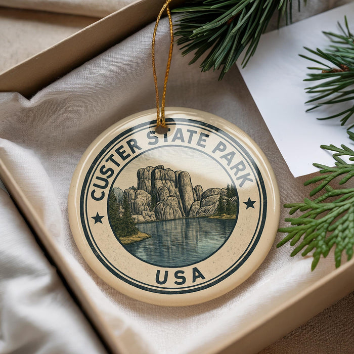 A decorative ornament with the text "CUSTER STATE PARK USA" and an illustration of a mountain landscape, hanging from a string.