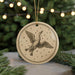 A round ornament featuring a flying goose against a starry night sky background, with a string of lights in the background.