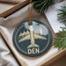 A circular ornament with a white airplane and the word "DEN" on it, hanging from a string.