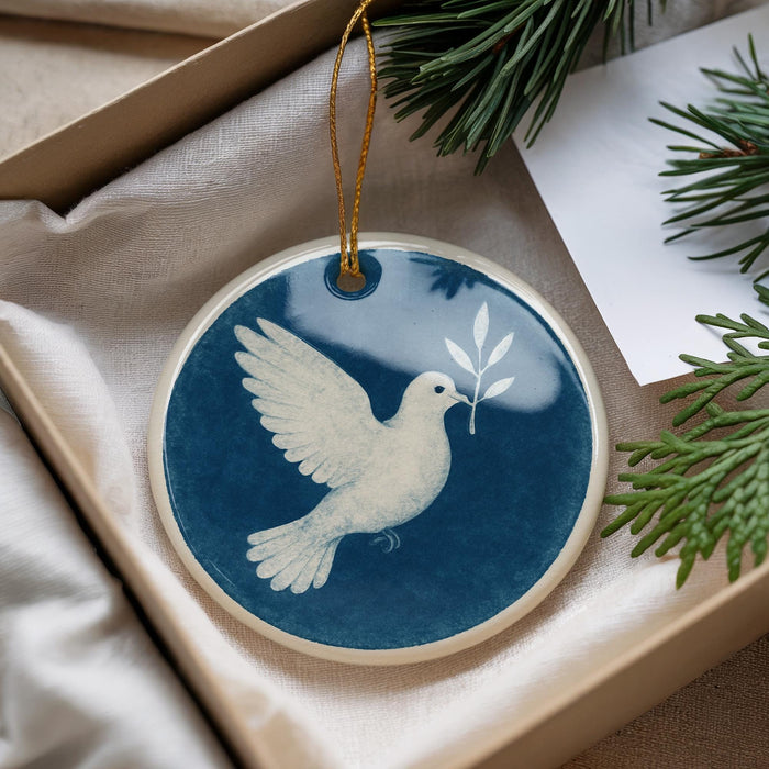 A blue and white ceramic ornament with a white dove in flight, hanging from a string.
