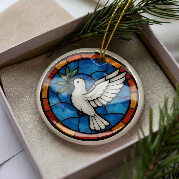 A decorative ornament in a box, featuring a stained glass design of a white dove with outstretched wings.