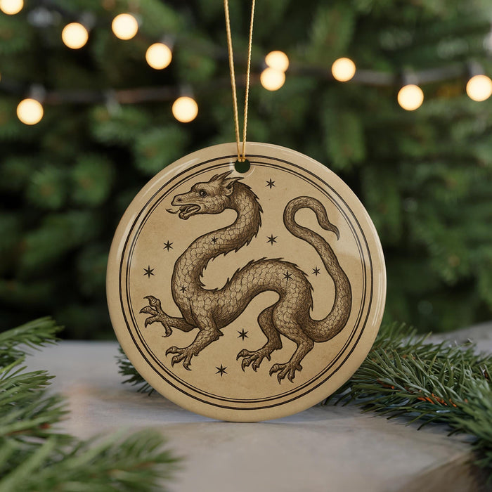 A circular ornament featuring a detailed illustration of a dragon, with a starry background, is displayed in front of a blurred Christmas tree.