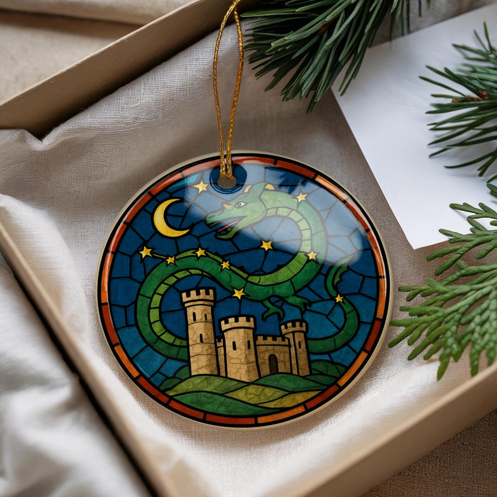 A decorative ornament in a box, featuring a castle and a dragon against a night sky background.