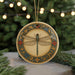 A decorative ornament featuring a detailed illustration of a dragonfly is displayed on a table, surrounded by pine branches and twinkling lights.