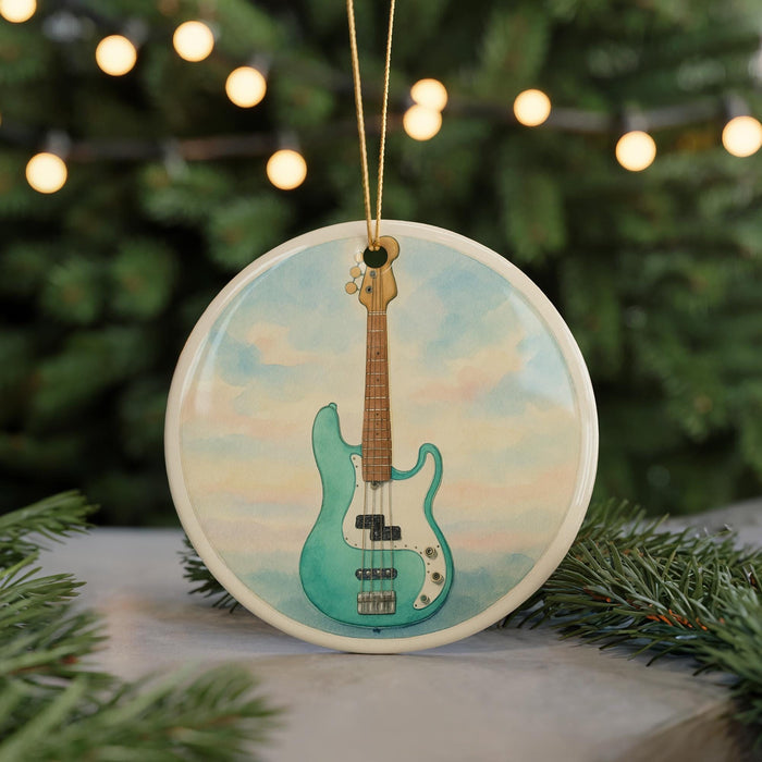 A round ornament featuring a blue bass guitar is displayed against a blurred background of a Christmas tree with twinkling lights.