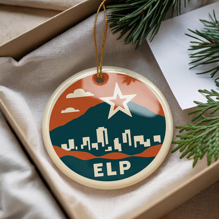 A round ornament with a cityscape design and a star, hanging from a string.