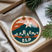 A round ornament with a cityscape design and a star, hanging from a string.