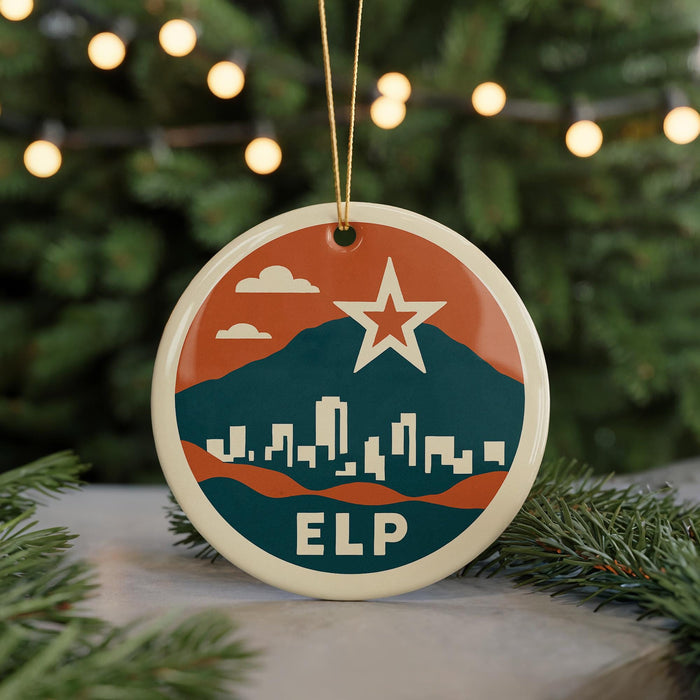 A round ornament with a cityscape design and a star, hanging from a string.