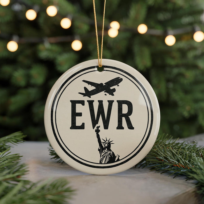 A white circular ornament with the letters "EWR" and a silhouette of the Statue of Liberty, hanging from a string.