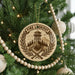 A Christmas tree decorated with a circular ornament featuring a mountain, a lookout tower, and crossed shovels, with the text "FIRE LOOKOUT" on the ornament.