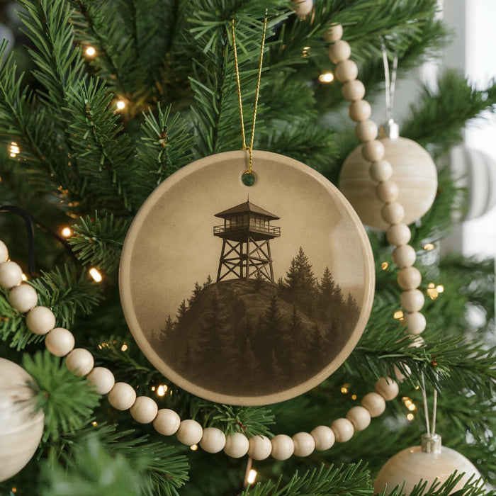 A Christmas tree decorated with ornaments, including a circular ornament featuring a lighthouse on a mountain.