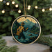 A round ornament depicting a person fishing in a river, with a mountainous landscape in the background.
