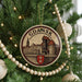 A circular ornament on a Christmas tree, featuring a drawing of a cityscape and the word "Gdansk" written on it.