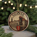A circular ornament with a drawing of a cityscape and the word "Gdansk" on it, hanging from a string.
