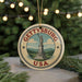 A round ornament with the text "GETTYSBURG USA" and an illustration of a statue, surrounded by greenery and a string of lights.