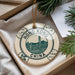 A decorative ornament featuring the text "HONG KONG CHINA" and a cityscape illustration, placed in a box with pine branches.