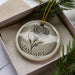 A decorative ornament in a box, featuring a detailed illustration of a flower and the word "JANUARY" written on it.