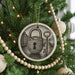 A Christmas tree decorated with ornaments, including a circular ornament with a lock and key design, surrounded by lights and greenery.