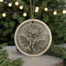 A decorative ornament featuring a chrysanthemum flower is displayed on a table, with a blurred background of a Christmas tree and twinkling lights.